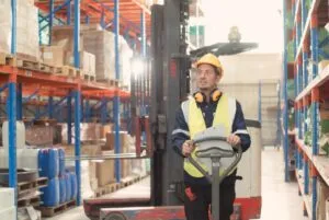 warehouse supervisor with reach truck behind him